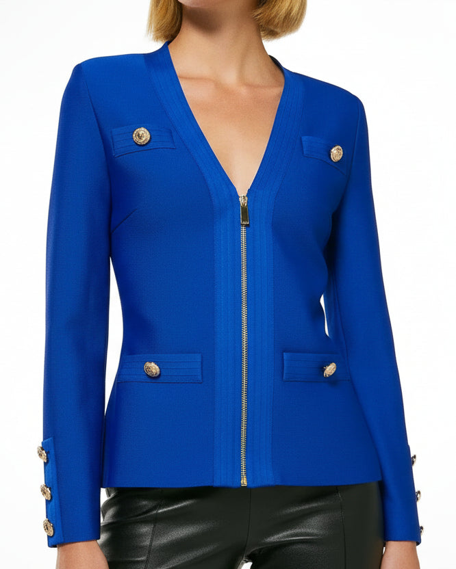 A woman wearing a royal blue bandage V-neck jacket with gold metal zipper and contouring features, paired with black pants.